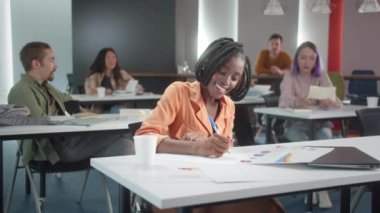 Çekici genç bir Afrikalı profesör seminere hazırlanıyor, öğrencileriyle konuşuyor ve birlikte gülümsüyorlar. Yüksek kalite 4k görüntü