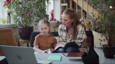 Bir kadın öğretmeniyle video bağlantısı yoluyla iletişim kurar. Çocuğu kanepede onun yanında oturuyor ev ödevini yapıyor. Yüksek kalite 4k görüntü