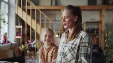 Kadın şarkı söylüyor ve piyano çalıyor. Kızı yanında oturuyor ve gülüyor. Onlar eğleniyorlar. Yüksek kalite 4k görüntü