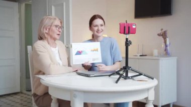 Gözlüklü yaşlı bir kadın ve bir kız onların iş fikirleri hakkında konuşuyor. Telefon kamerasında şemalar ve grafikler var. Sunumu koruyorlar. Çağrı bittikten sonra sarılırlar ve...