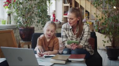 Özel öğretmen çocukla birlikte çalışıyor. Egzersizleri telefondan okuyor ve kızla iletişim kuruyor. Yüksek kalite 4k görüntü