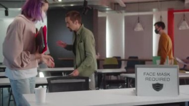 Koruyucu maskeli enerjik genç öğrenciler seminer için hazırlanıyorlar, birlikte konuşuyorlar ve öğretmeni bekliyorlar. Yüksek kalite 4k görüntü