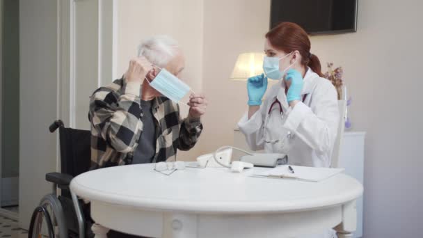 Orvos Megmondja Egy Tolószékes Nyugdíjasnak Hogyan Vegyen Fel Védőmaszkot Kiváló — Stock videók