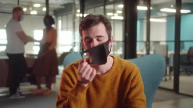 Haki gömlekli genç bir öğrenci koruyucu yüz maskesini çıkartıyor ve gülümseyen kameraya bakıyor. Yüksek kalite 4k görüntü