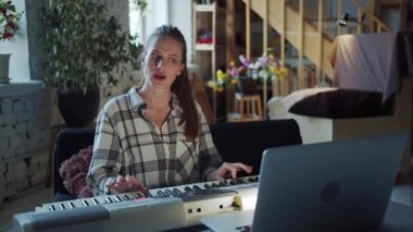 Kadın müzikte yeni. Piyano çalmakla ilgili bir video dersi buldu. O bir dizüstü bilgisayarın önünde oturur ve oynar. Yüksek kalite 4k görüntü