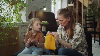 Bekar bir anne bir kızla konuşur. Birbirlerine yün bir eşarp örüyorlar. Çocuk örgü iğneleriyle oynuyor. Yüksek kalite 4k görüntü