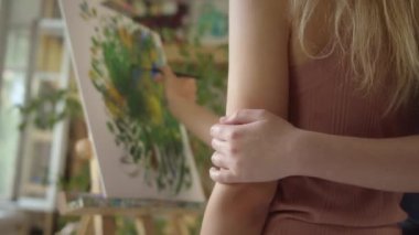 Stüdyoda iki genç kız arkadaş dikiliyor ve birlikte yeşilin tonlarında bir resim çiziyorlar, yakın çekim. Yüksek kaliteli FullHD görüntüler