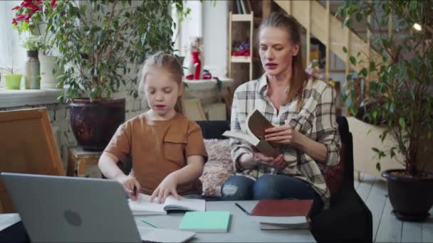 Kvinna Hjälper Sin Dotter Med Läxor Hon Plockar Upp Läroböcker — Stockvideo