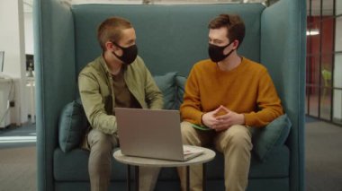 Üniversitedeki dinlenme yerinde birlikte oturan genç öğrenciler, yavaş çekimde ortak projeleri hakkında tartışıyorlar. Yüksek kaliteli FullHD görüntüler