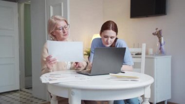 Bir kadın büyükannesine işinde yardım eder. Belgeleri inceler ve bilgisayardaki masaları doldururlar. Yüksek kalite 4k görüntü