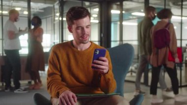 Genç bir erkek öğrenci sandalyede oturur ve internetteki komik yazıları okur, kapat. Yüksek kaliteli FullHD görüntüler