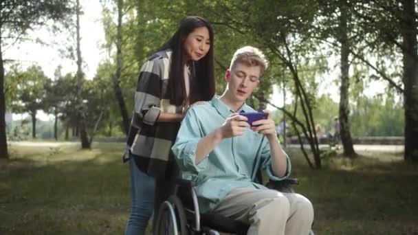 Una Giovane Ragazza Asiatica Suo Fidanzato Biondo Disabile Stanno Guardando — Video Stock