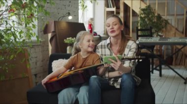 Geniş bir dairede kızıyla oturan bir kadın. Annem telefonda gitar hocasıyla konuşuyor. İpleri koparmaya çalışan bir kız. Yüksek kalite 4k görüntü