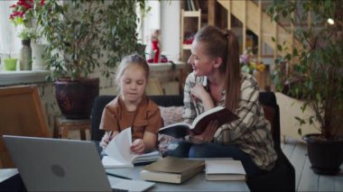 Çocuk dikte altında bir deftere yazıyor, annesi ne yazdığını kontrol ediyor.