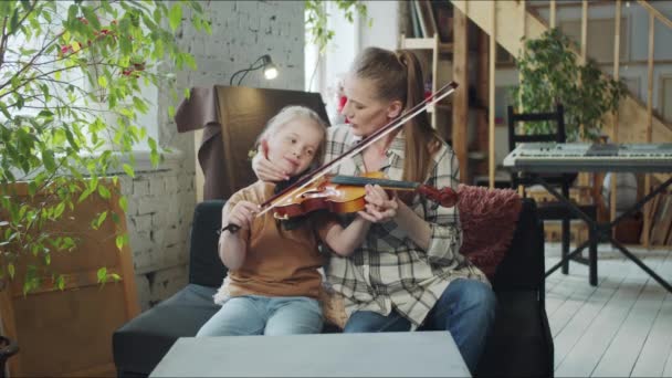 Μια γυναίκα βοηθά ένα παιδί να πάρει ένα βιολί και διδάσκει πώς να παίξει — Αρχείο Βίντεο