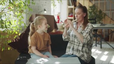 Anne kızına nasıl flüt çalınacağını gösteriyor.