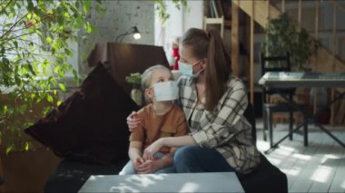 Anne ve kızı birbirlerine bakıp koronovirüsten maskelerini çıkarıyorlar.