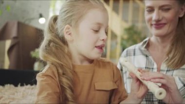 Kız annesiyle flüt çalıyor ve internetten ders almayı öğreniyor.