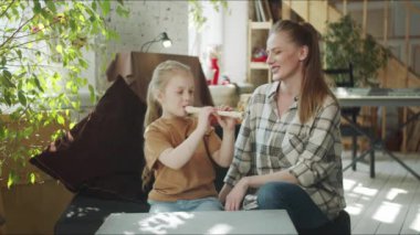 Küçük bir kız, annesi için rahat bir oturma odasında flüt çalıyor.