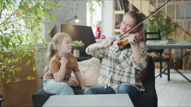 Η μαμά παίζει μουσική στο βιολί, και η κόρη της δίνει συμβουλές σε μια γυναίκα. — Αρχείο Βίντεο