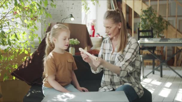 En kvinna berättar för sin dotter hur man använder en flöjt och visar sin enhet — Stockvideo