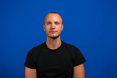 mavi arka plan üzerinde duran yakışıklı bir adam portresi.