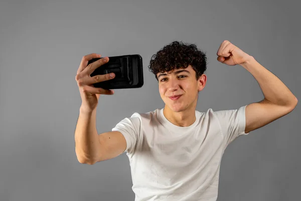 Portret van opgewonden jongeman op zoek naar smartphone geïsoleerd op grijze achtergrond. Winnaars concept — Stockfoto