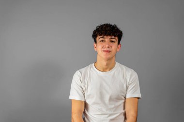 Gri bir arka planda izole edilmiş mutlu genç adamın portresi.