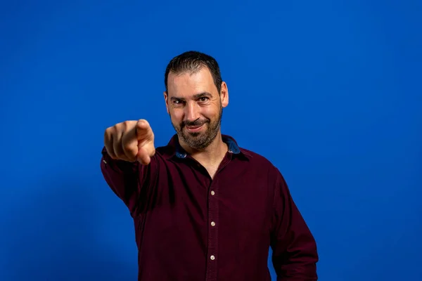 Portret van enthousiaste aantrekkelijke man aangeeft op camera geven knipoog geïsoleerd op blauwe achtergrond — Stockfoto