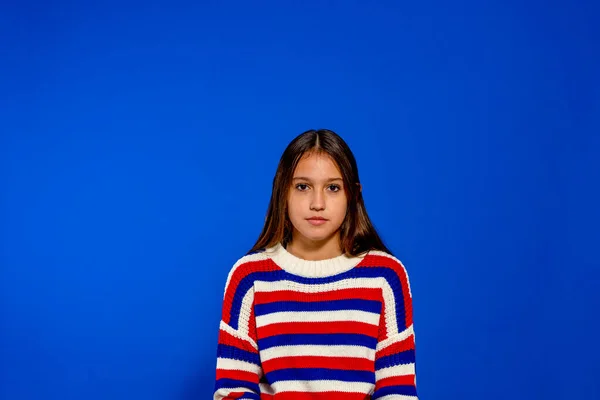 Приваблива молода іспаномовна жінка, одягнена в смугастий светр пози для переднього портрета ізольовані на синьому студійному тлі Ліцензійні Стокові Зображення