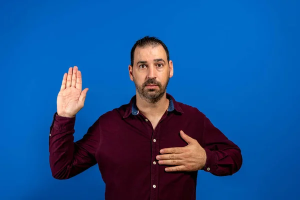 Young handsome man wearing casual shirt standing over isolated blue background. Swearing with hand on chest and open palm, making a loyalty promise oath — Fotografia de Stock