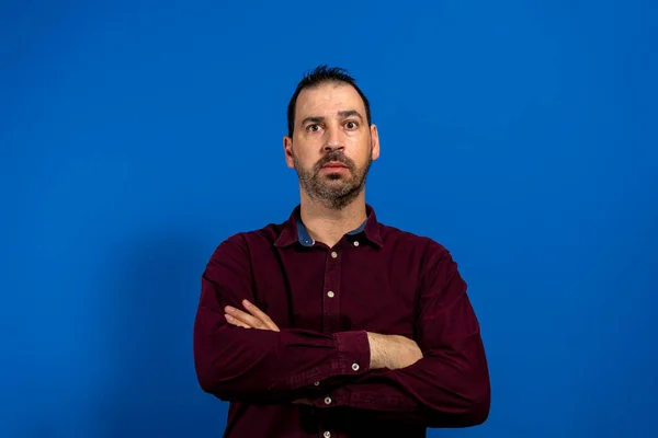 Bandiera di giovane bell'uomo con camicia viola, in piedi con le braccia incrociate, isolato su sfondo blu studio — Foto Stock