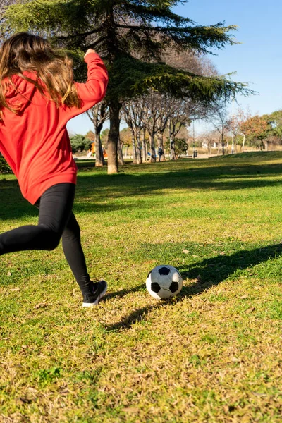Joven atleta corriendo para patear una pelota de fútbol en un hermoso parque con césped natural. Enfoque selectivo. — Foto de Stock