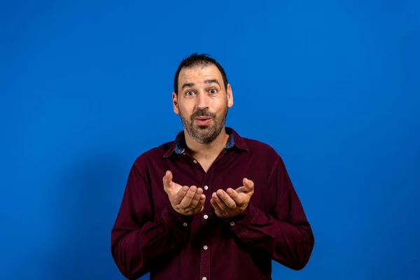 拉丁美洲男人，留着胡子，身穿紫色衬衫，双手被隔离在蓝色工作室的背景下。招待费概念. — 图库照片