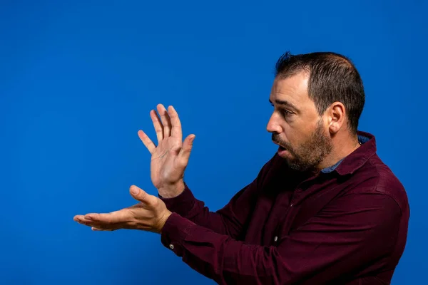 Homem barbudo latino vestido com uma camisa roxa isolada no fundo do estúdio azul, ele está jogando uma fama kame imitando Son Goku de Dragon Ball, um de seus heróis da juventude — Fotografia de Stock