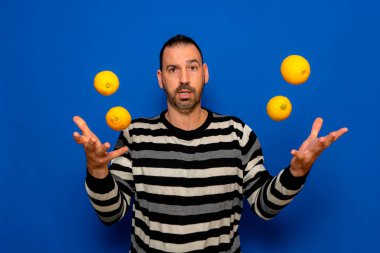 Çizgili süveter giyen, mavi duvar arkasında yalnız poz veren komik bir adam, stüdyo portresi. Sağlıklı moda yaşam tarzı, insan duyguları, soğuk sezon konsepti. Kopyalama alanı oluşturun. limon atmak.