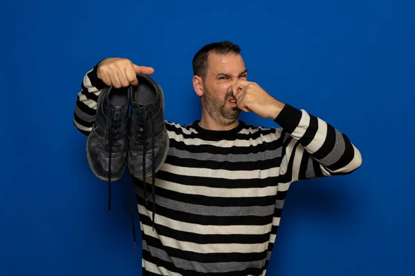 Un hombre tiene zapatillas en sus manos. Qué mal olor. Patas apestosas, hongos en las piernas. — Foto de Stock