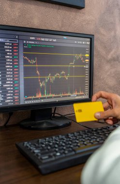 Dijital grafik yükseliyor ve düşüyor, cihaz ekranda ve kredi kartıyla el ele. Şirket iletişimi, borsa ön planda değişiklikler. Çevrimiçi ödeme kavramı