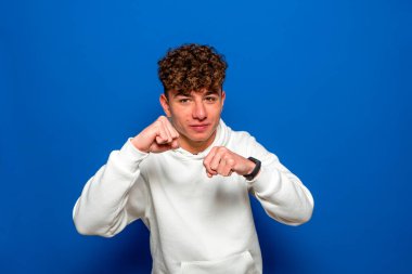 Yakışıklı bir adam yumruk atıyor, yumruğunu sıkıyor ve gölge boksu yapıyor. Sıradan giyinmiş biriyle kavga ediyor..