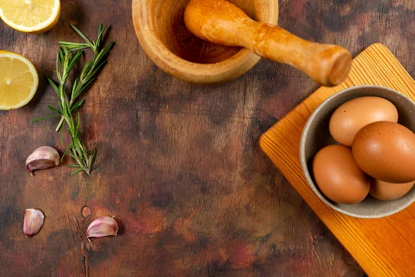 Top view of a composition of ingredients and kitchen utensils to prepare the tasty garlic sauce with egg and oil on an old wooden table — Stock Photo, Image