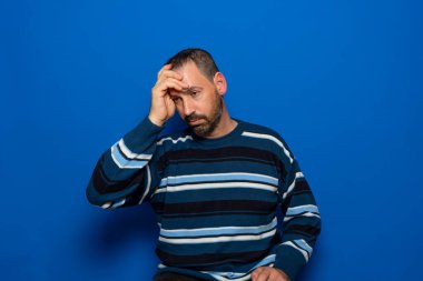 Kışlık süveter giyen yakışıklı İspanyol bir model izole edilmiş arka planda üzgün ve maddi durumu hakkında endişeli görünüyor. Endişe sorunu