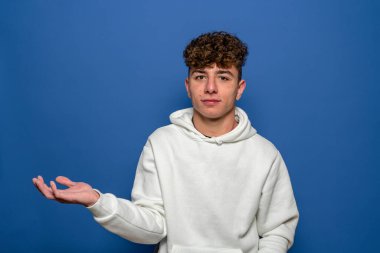 Kafkasyalı yakışıklı bir adam avucunun içinde hayali bir şey tutuyor. Mavi arka plan üzerine bir ilan vermek için..