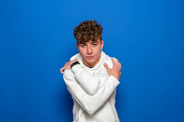 Kendine sarılabileceksen bir kız arkadaşa ihtiyacın yok. Bencil duygu konsepti. Beyaz kazaklı, ciddi bir beyaz çocuk kendine sarılıyor.