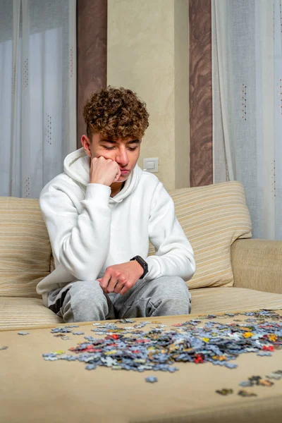 Young Man Sitting Sofa Doing Puzzles Isolated Place — Φωτογραφία Αρχείου
