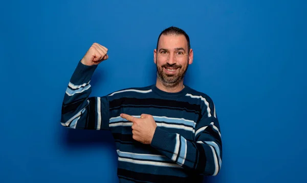 Spanish Bearded Man Striped Pullover Pointing Finger Biceps Muscles Demonstrating — Fotografia de Stock