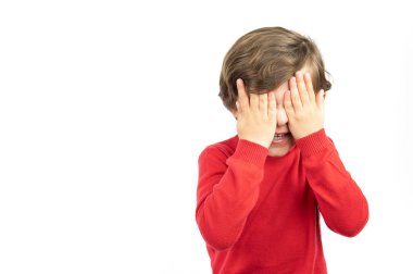 Kızgın küçük çocuk ellerini beyaz bir arka planda tutarak yüzünü kapatıyor.