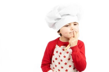 Sevimli küçük çocuk / çocuk Şef gibi giyinmiş ve mutfak aletleri taşıyor, beyaz arka planda tek başına duruyor.