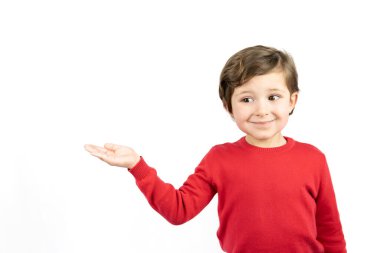 Kırmızı kazaklı çocuk beyaz arka planı işaret ediyor. Boşluğu kopyala.