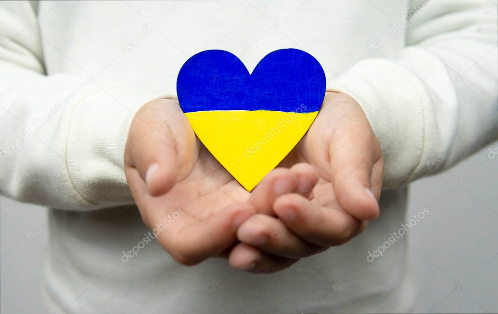 Child holding a heart with the flag of Ukraine with both hands.Peace, Stop war.
