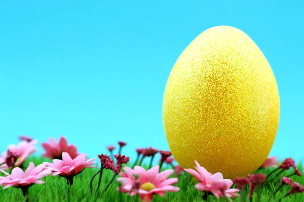 Golden easter egg on a meadow with pink flowers, goldenes Osterei auf Blumenwiese — Stock Photo, Image